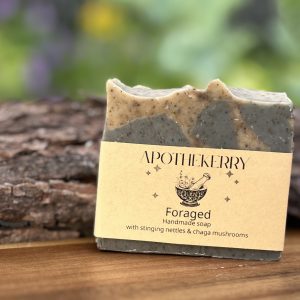 Handmade Foraged soap by ApotheKerry with natural grey and tan layers, displayed on a wooden surface outdoors
