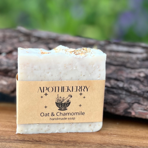 Handcrafted Oat & Chamomile soap by ApotheKerry, set against wood and nature, evoking calm, softness, and gentle care.