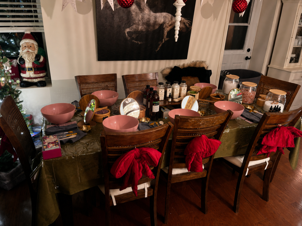 A beautifully arranged ApotheKerry spa party setup featuring bowls, mirrors, botanical ingredients, and self care stations around a dining table decorated for a cozy gathering.