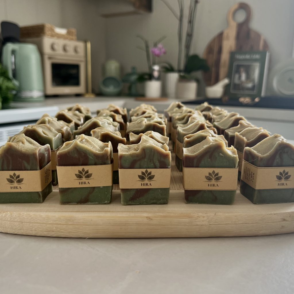 Rows of handcrafted Hira mini soaps displayed on a wooden board in a cozy kitchen