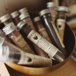 A bowl filled with ApotheKerry powdered face masks in tubes displayed on a wooden shelf.